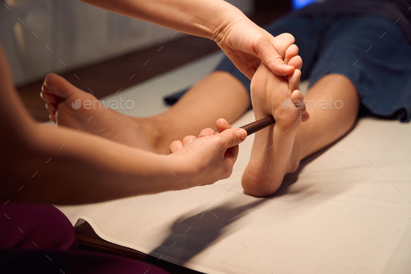 Reflexology - Foot Massage with Wooden Massage Tool. Stock Photo