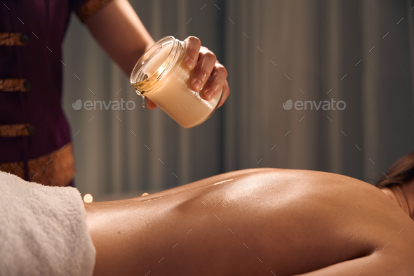 Spa therapist preparing patient for scented candle massage