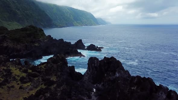 Aerial shot above Fajã do Ouvidor in São Jorge Island, towards to the rocky blue coast. Azores, Port alt