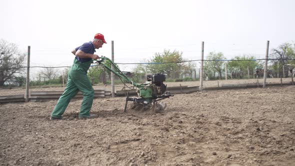 Man Plowing the Land in the Garden on Sky Background