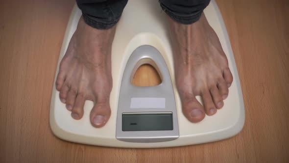 Male Weighting on Floor Scales in Domestic Room, Close Up Feet View
