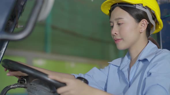 Asian female worker driving forklift truck