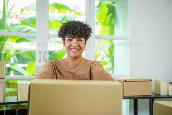 Asian female merchant preparing a package box to deliver to customers.
