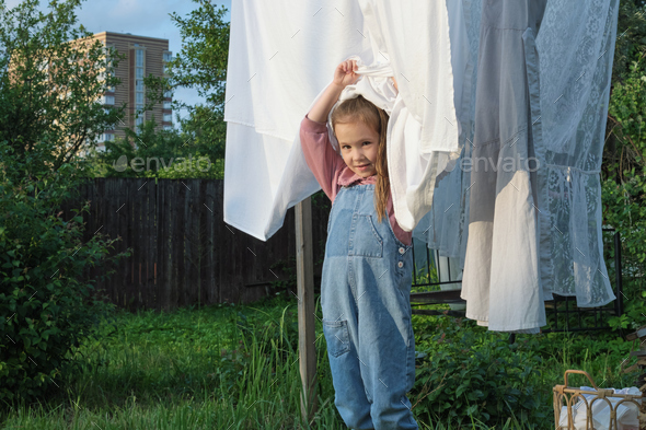 Sustainable Living. Amidst a backdrop of air-dried laundry, a vibrant child in a denim jumpsuit