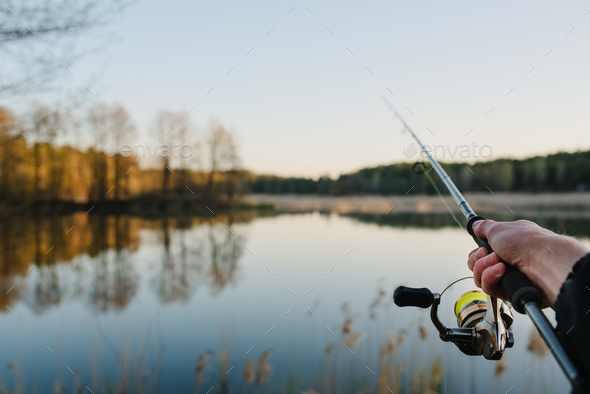 Fishing. Fisherman with rod, spinning reel on the river bank