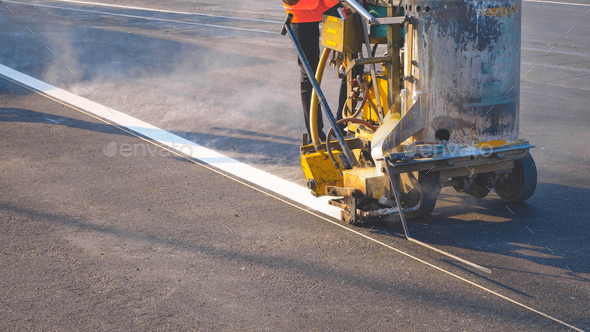 Low section of road worker with marking machine is painting traffic white line on asphalt road