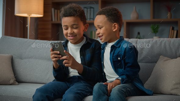 Children gadget addiction two happy laughing African American little boys brothers browsing mobile