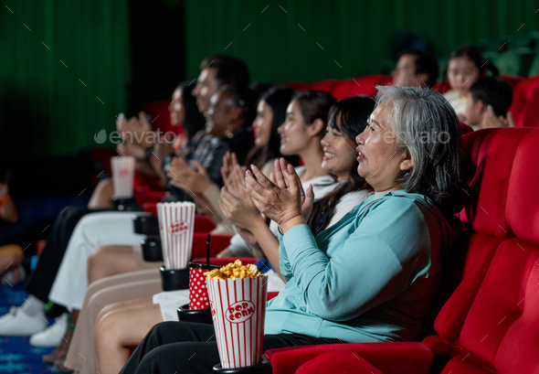 Side view of multiethnic and multigeneration people clap hands during watch movie together