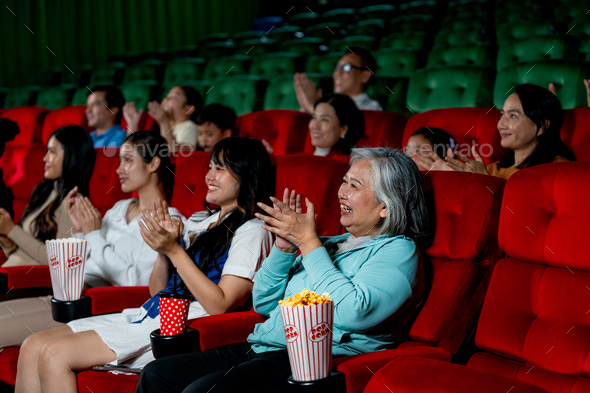 Wide shot of multiethnic and multigeneration people clap hands during watch movie together