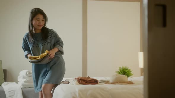happiness travel asian female woman arrange cloth and stuff after checkin at hotel on the bed