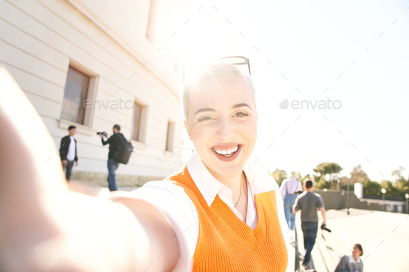 Portrait of a Caucasian student girl laughing and looking at camera selfie. Young shaved head woman