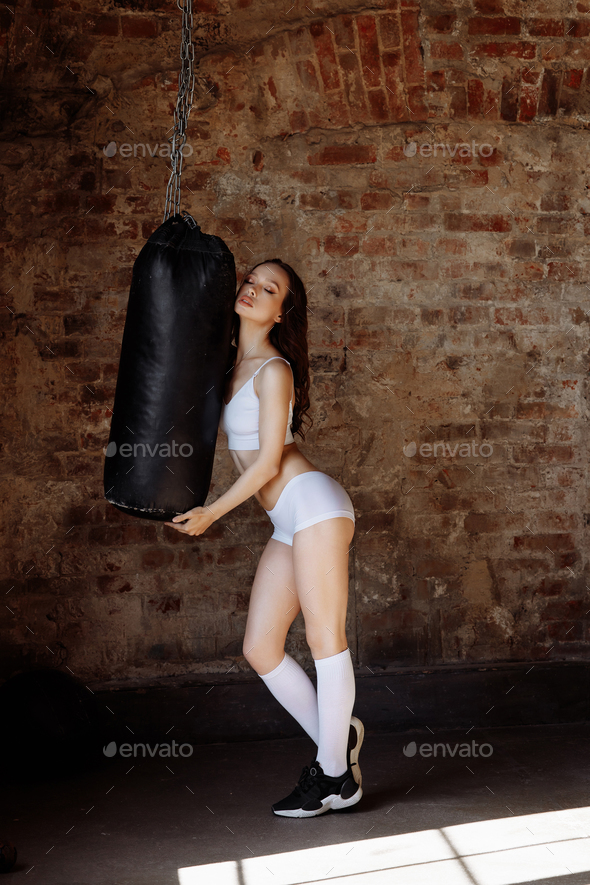 Awoman with an athletic build on the background of a punching bag
