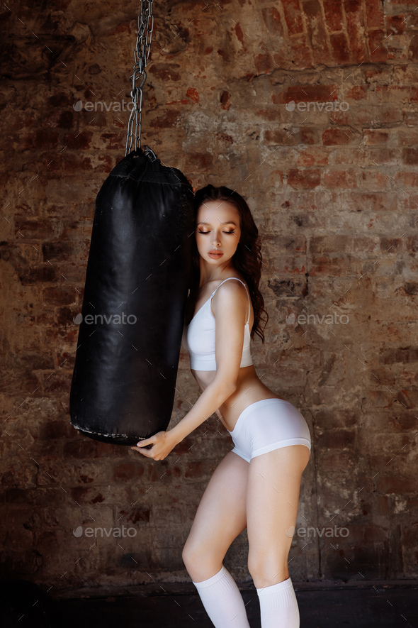Awoman with an athletic build on the background of a punching bag