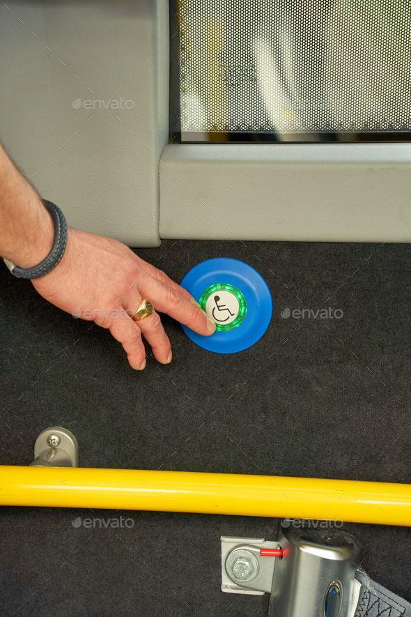 Man hand pushing the blue button of the disabled people door in public transport bus, Paris, France