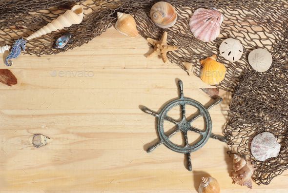 Top view of captains wheel with fishing net and sea shells on