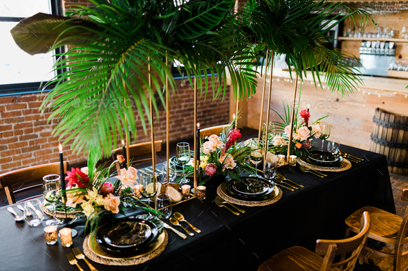 Beautifully arranged black table with floral arrangements and palm leaves for a fancy dinner