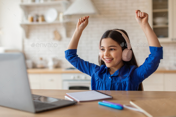 Joyful Arabic School Girl At Laptop Shaking Fists At Home
