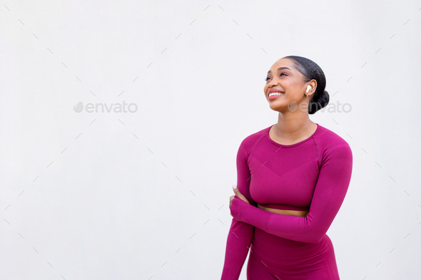 Sportive happy black lady wearing wireless earphones listening to music