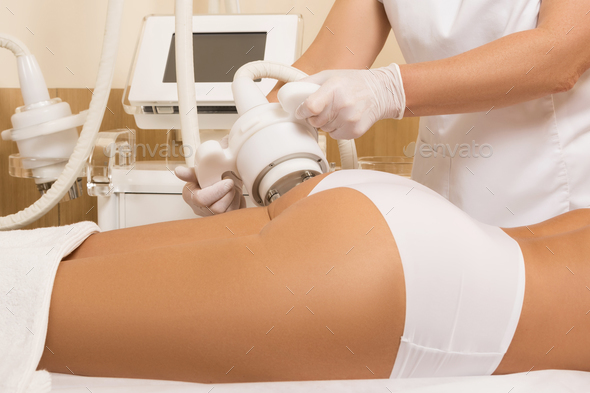 Woman during anticellulite massage or figure correction procedure in clinic