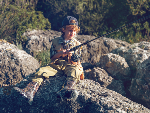 Serious Boy Sitting on Riverside while Fishing Stock Photo - Image