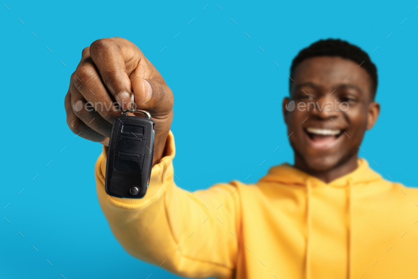 Automative car key in black man hand, blue background