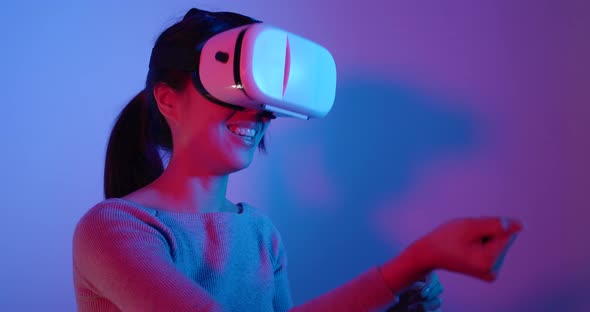 Woman looking though virtual reality device over red and blue light alt