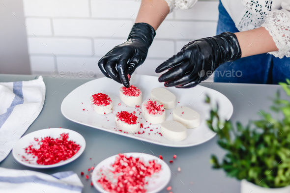 pastry chef decorates the bird's milk souffle cakes with freeze-dried raspberries and strawberries.