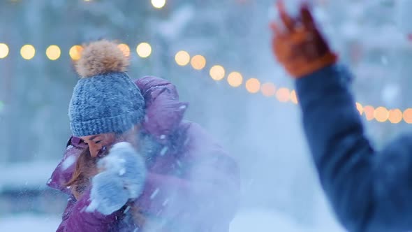Girl in Warm Jacket and Hat Throws Snow with Happy Boyfriend