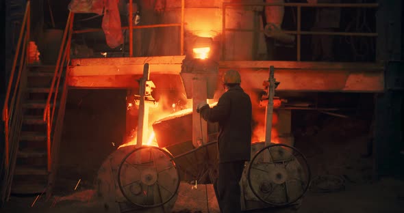 Foundry, a man pours molten metal into the mold