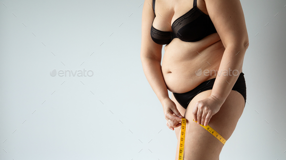 Closeup shot of a chubby thick female in lingerie measuring her thigh Stock  Photo by wirestock
