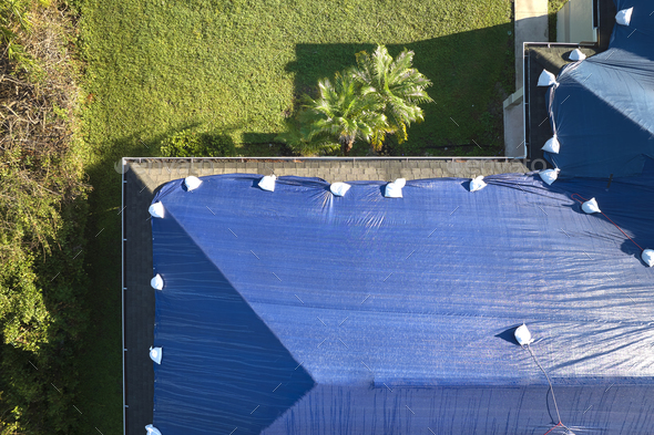 Top view of leaking house roof covered with protective tarp sheets against rain water