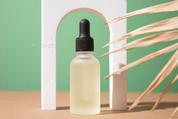 Cosmetic bottle with body and face oil on palm leaf, summer natural cosmetics, serum, facial oil