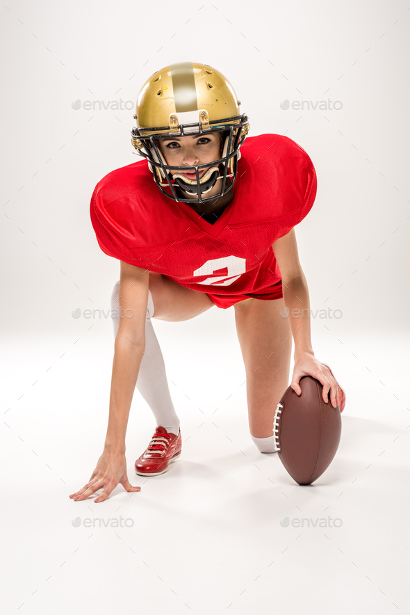 Beautiful female american football player in helmet posing with ball  isolated on grey Stock Photo by LightFieldStudios