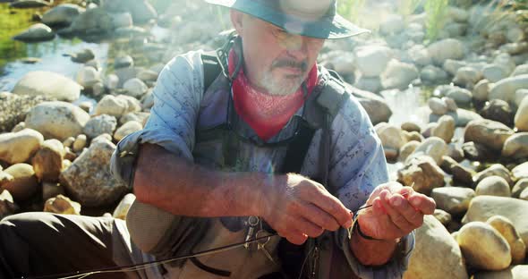 Fly fisherman putting new string on fishing rod alt
