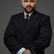 Bald and bearded man in a black suit holds a pistol, exuding power - PhotoDune Item for Sale