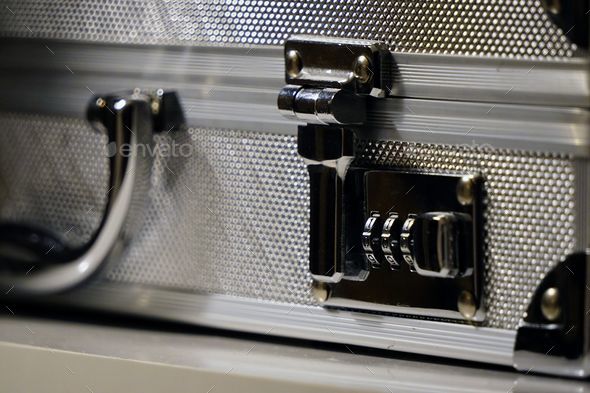 Closeup of an aluminum attache case lock placed on a white surface
