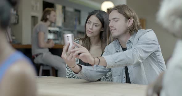 Man and woman taking self photograph with mobile phone in pub