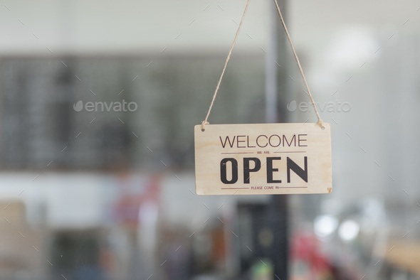 yes we\'re open sign on the glass of the doors in store. welcome sign at the store