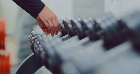 Metal Dumbbells Lie in a Row on a Rack in the Gym alt