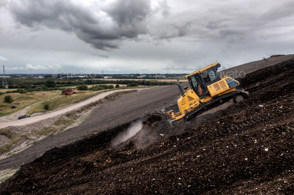 A bulldozer on a slope moving waste on a landfill site
