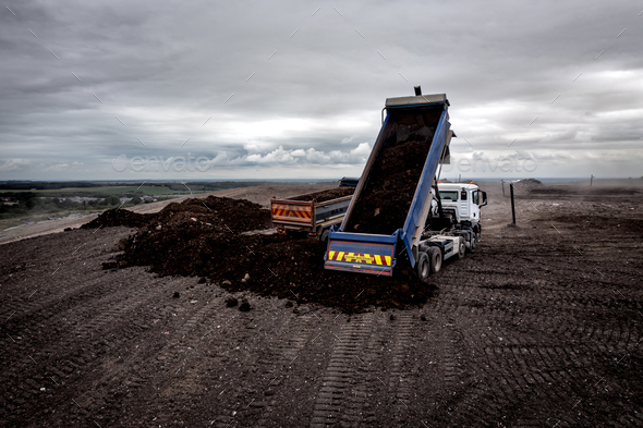 Aerial view of a tipper truck with raised trailer on a landfill site