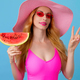 Woman with watermelon in pink swimsuit, fashionable hat, smiling enjoys summertime for pool party.  - PhotoDune Item for Sale