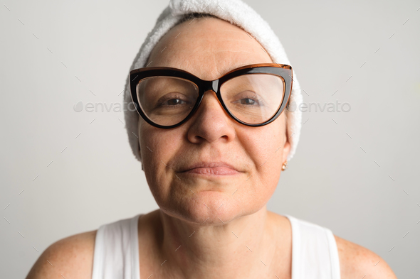 Middle-aged woman lookin in a mirror and checking bags under the eyes, skin and wrinkles. Skincare