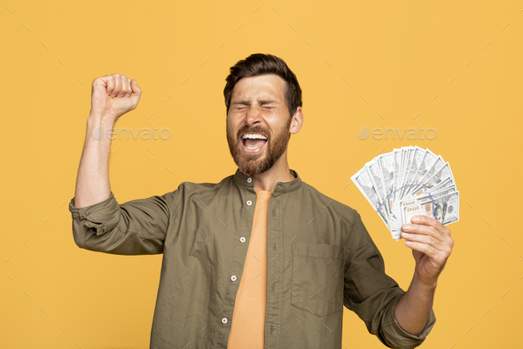 Lucky winner. Overjoyed middle aged man holding money cash in hands, euphoric male celebrating big
