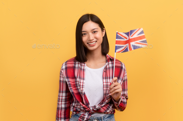 Cheerful asian lady student holding England flag, enjoying tutoring or studying language, posing on