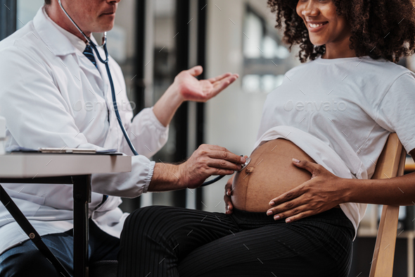 Male gynecologist doctor checking african american pregnant woman ...