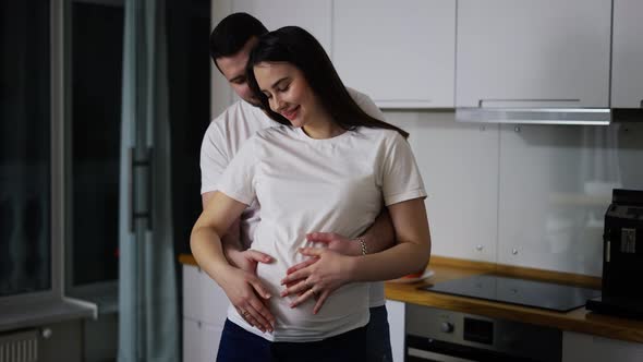 Husband Gently Stroking Pregnant Wife Tummy Indoors in Slow Motion alt