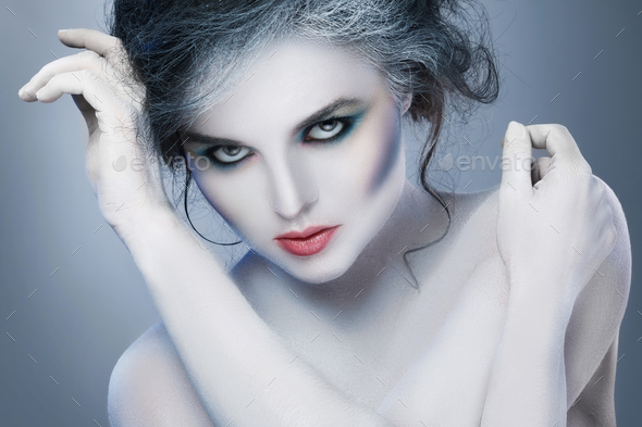 Woman in white body-art in creative image of winter, snow queen, or another sad or evil character