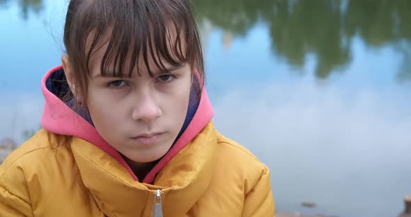 Teen sit alone by water. alt