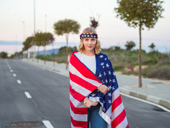 Vertical shot of a blonde Caucasian woman from Spain wearing the American flag and headband